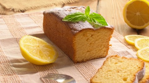 Lemon pound cake on rustic wooden background with lemon and mint. Rotation.
