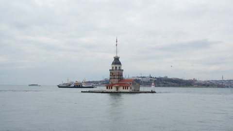 Boats floating near Maiden Tower in Bosphorus Istanbul. Ships on waves, famous Maiden Tower and Istanbul cityscape at cloudy day