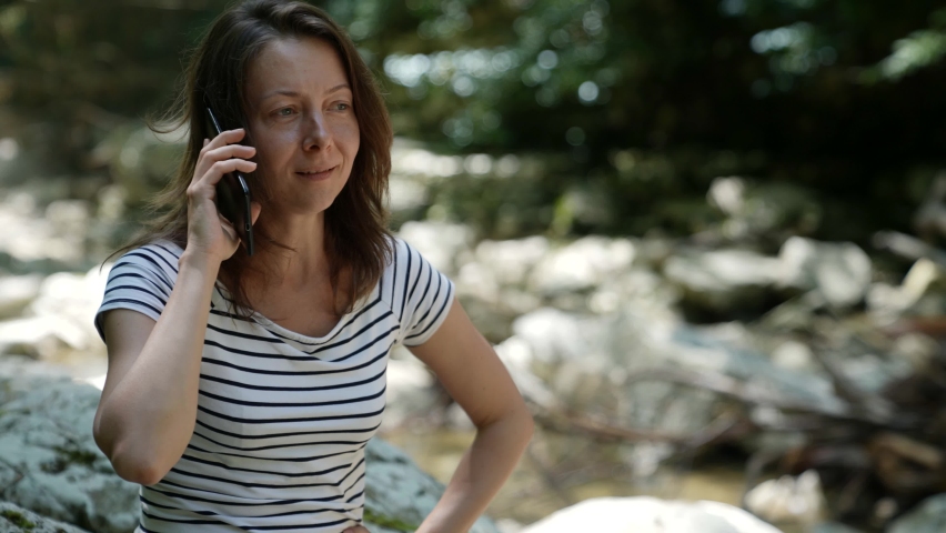 an adult natural woman is sitting on the street and emotionally waving her hands around talking on the phone