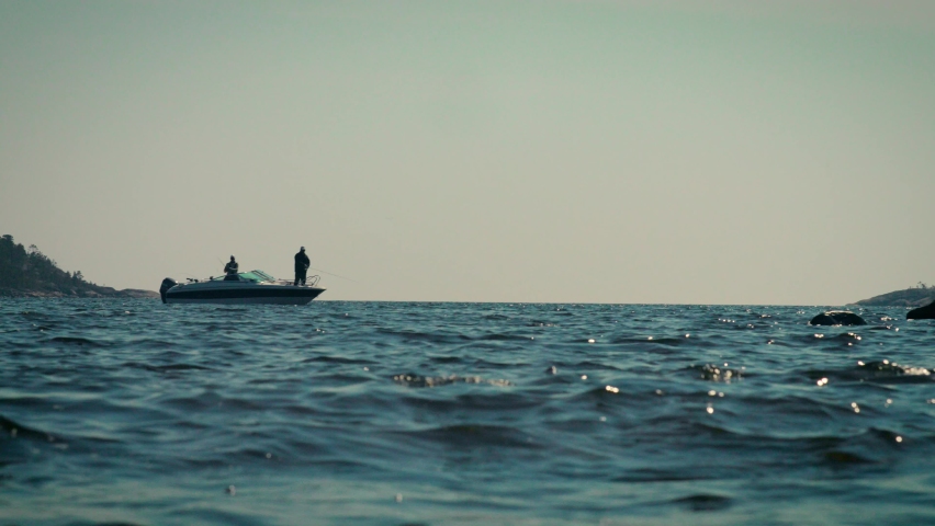 Fishing boat on the ocean. Two people on the boat. 120 fps, slow motion, 4K. Shot in Byviken, Häggdånger, Sweden on a Canon C300 III.