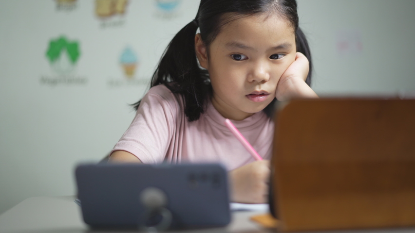 Asian child student or kid girl write and learn from home school or people study online on computer tablet and video call learning on smartphone with enjoy to vocabulary english words in classroom Royalty-Free Stock Footage #1078014176