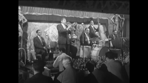 CIRCA 1950s - A band of men play their instruments and sing on a stage in front of their audience in the 1950s.