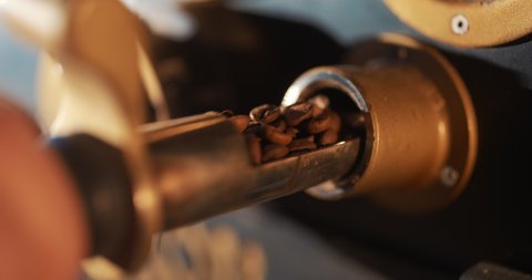 Roasted coffee beans fly and spin on a black background in slow motion. Production of fresh fried coffee beans roasting factory process. Prepared coffee beans mixing around on a cooling plate of oven.