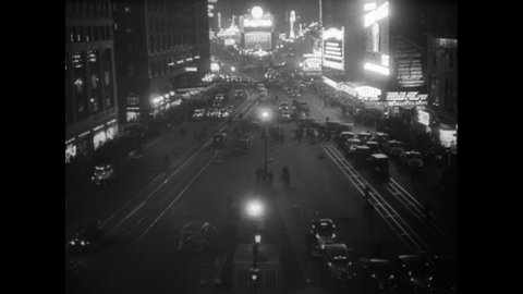 CIRCA 1933 - Times Square sees heavy foot traffic and vehicular traffic at night in New York City.