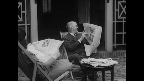 CIRCA 1940s - A British statesman reads a newspaper in his front yard.