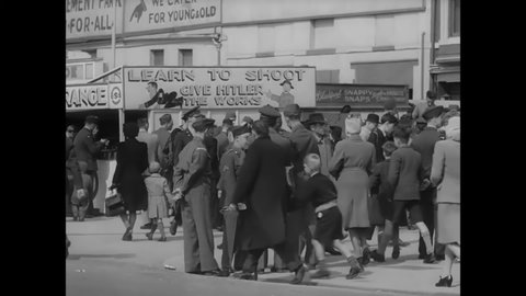 CIRCA 1940s - Men and women of the British Army walk down a boardwalk, passing anti-Nazi games.