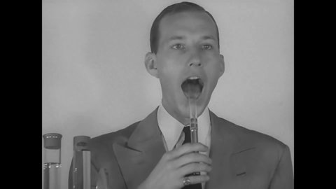 CIRCA 1940s - A DuPont scientist places a glass tube into his mouth.
