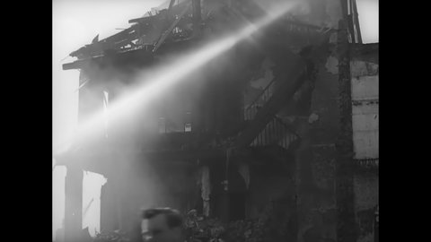 CIRCA 1940s - Firemen hose down enormous damaged buildings in war-torn Britain.