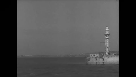 CIRCA 1940s - A British Navy cruiser sails into port.