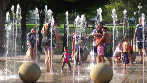SAN JOAQUIN VALLEY, CALIFORNIA - CIRCA 2021- people bathe in a public fountain during a scorching heat wave during drought conditions.