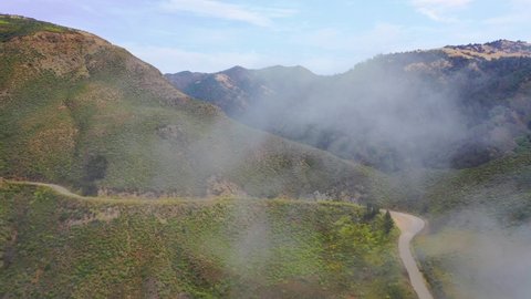 CALIFORNIA - CIRCA 2021 - Aerial shot through the fog reveals the a narrow road in the remote mountains along California's Highway One.