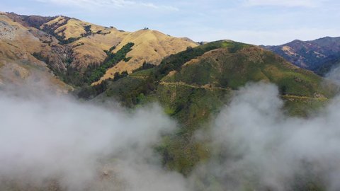 BIG SUR, CALIFORNIA - CIRCA 2021 - Rising aerial shot through the fog reveals the remote mountains along California's Highway One.