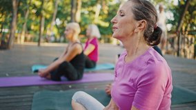 Keep calm and breathe. Close up portrait of peaceful senior woman meditating outdoor, practicing yoga with group of mature friends, tracking shot - Powered by Shutterstock - Get 15% off with code: PIKWIZARD15