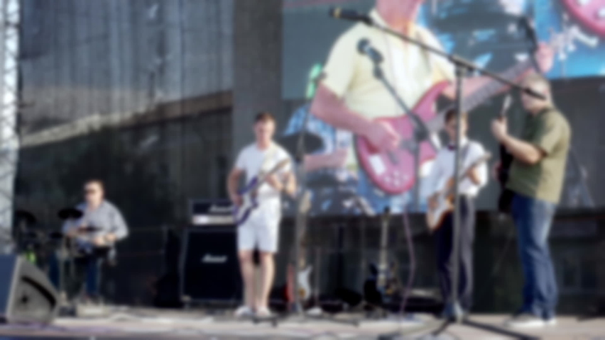 Defocused video of musicians performing on a street stage.