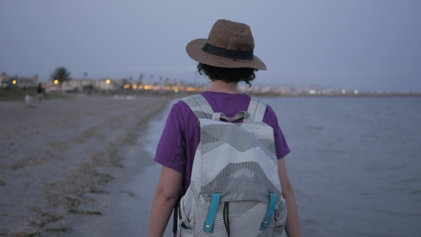 A woman walks on the sand on the beach as night falls