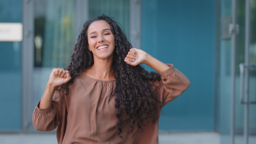 Curly brunette female model dancer with long hair stylish hairstyle woman girl dances actively moves to music outdoors on street turns spins rotates around making movements with hands whirling dancing | Shutterstock HD Video #1078039958