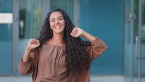 Curly brunette female model dancer with long hair stylish hairstyle woman girl dances actively moves to music outdoors on street turns spins rotates around making movements with hands whirling dancing - Powered by Shutterstock - Get 15% off with code: PIKWIZARD15