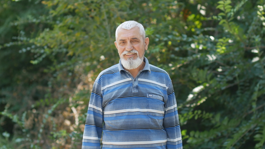 portrait of senior caucasian man with gray hair and beard. handsome smiling grandfather, senior citizen with white healthy teeth, dental smile. Outdoors