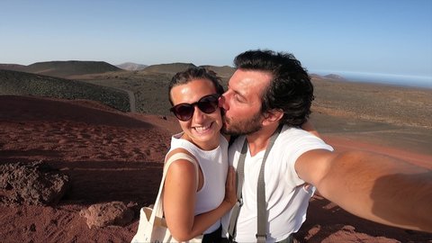 tourist is standing on the Lanzarote valley with red mountains in the national park Timanfaya in Lanzarote, Canary islands and taking selfie photo