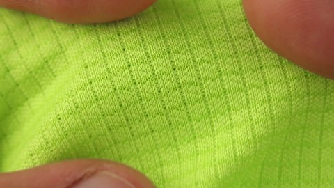 hands testing and stretches green sports breathable synthetic fabric, vapor permeable textile for running and fitness, close-up macro view