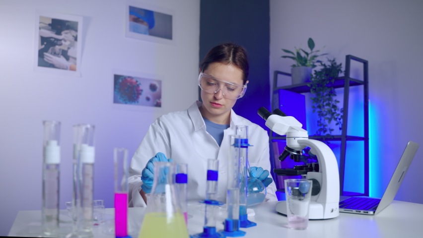woman scientist is experimenting in chemical laboratory, mixing liquids in test tube, student or laboratorian is examining chemicals, a Healthcare Video by Polina B
