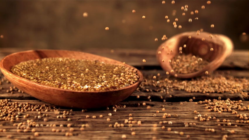 Super slow motion on a wooden table falling grains of fresh mustard. On a wooden background. Filmed on a high-speed camera at 1000 fps.