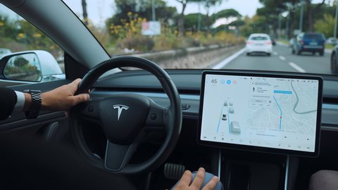 ROME, ITALY - APRIL 28, 2021: Back view of innovative Tesla car interior with touchscreen monitor display, illuminated car dashboard with different navigating and informative apps. High quality 4k