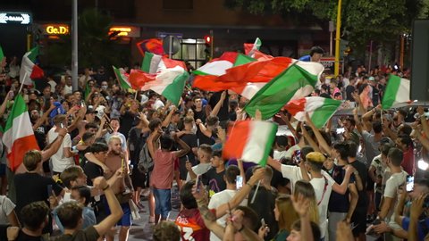 ROME, ITALY - JULY 11, 2021: Happy Italian fans and supporters with waving flags blocking roads after the victory of football sport team in UEFA EURO 2020, crowd of street fans dancing on the road
