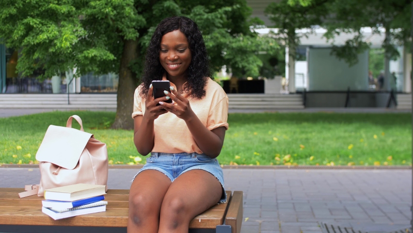 technology, education and people concept - happy smiling african american student girl with smartphone and books in city Royalty-Free Stock Footage #1078071392