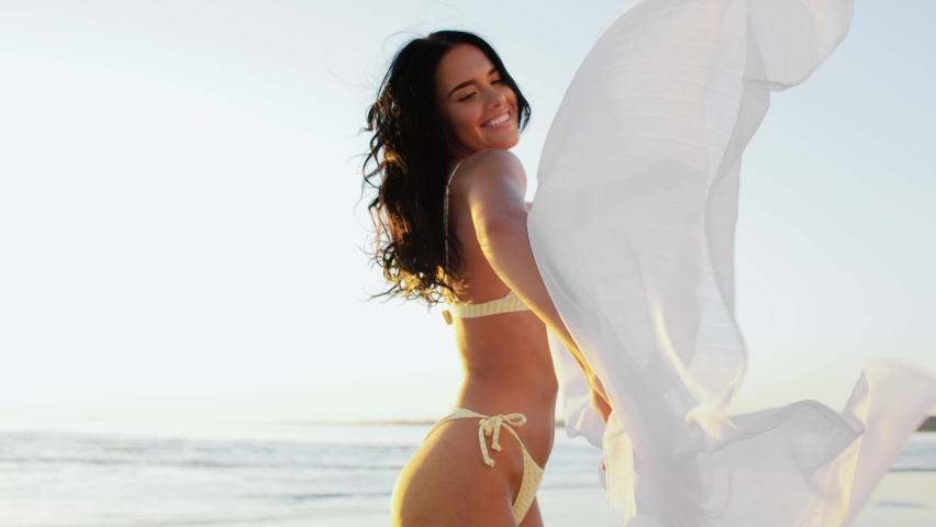  summer and swimwear concept - happy smiling young woman in bikini swimsuit with pareo on beach Royalty-Free Stock Footage #1078071440