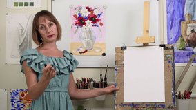 Art class online education. Spbas Positive lady artist draws scheme of future still life on paper sheet at wooden easel in decorated studio closeup