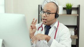 Doctor talks to patient via online video conferencing with computer wearing headset. Explain about taking medications to treat illnesses.
