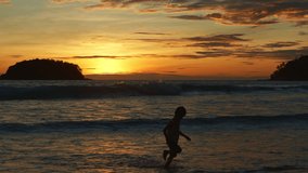 
A boy jumping on white waves in golden sunset.
Paradise beach blue sea, and clear sand landscape background.
funny kid and travel concept.