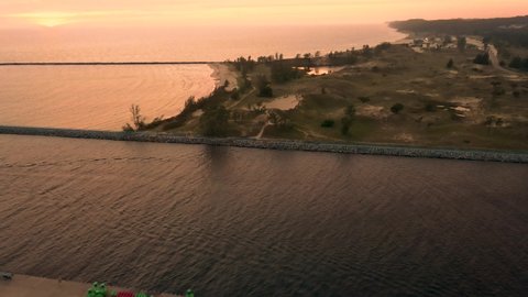 Smooth pan over the channel of Muskegon Lake and Lake Michigan with side motion.