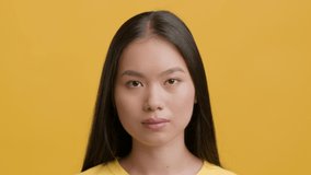 Disgust Emotion. Asian Woman Frowning Feeling Bad Smell Shaking Head In Disapprovement Posing Over Yellow Studio Background. Portrait Of Disgusted Female Smells Unpleasant Smelly Stink