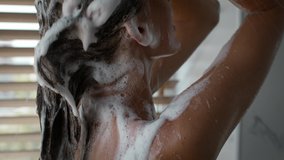 Female Haircare. Unrecognizable Lady Washing Long Hair Covered With Foam Applying Shampoo Standing Back To Camera In Modern Bathroom Indoors. Woman Taking Shower And Caring For Hair. Cropped
