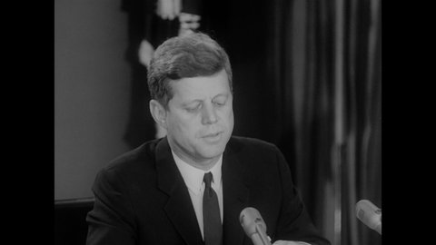 1960s: President John F. Kennedy delivering speech into microphones.