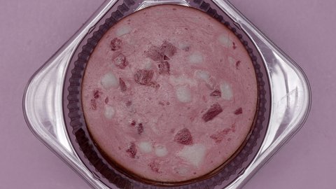 Thinly Sliced Veal Sausage In A Vacuum Package Rotating On A Pink Background. Close Up. Top View.
