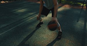 Professional american basketball player cool guy in action with ball dribbling on court outdoors, close up