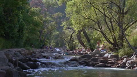 A group of people relaxing and enjoying a small creek with gently flowing cascades in Boulder Colorado