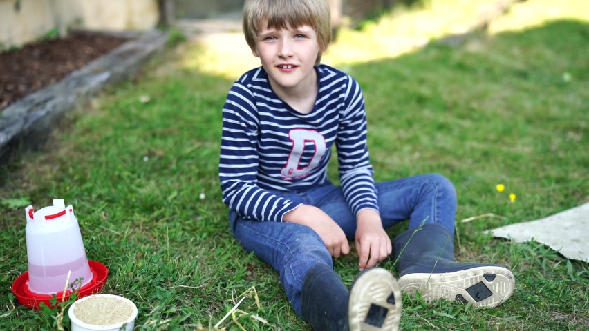 Blond boy waiting and sitting in grass