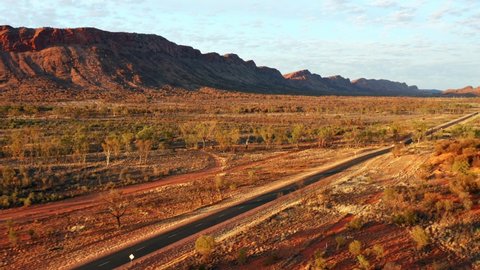 Long Asphalt Road Amidst The Wilderness With A View Of West MacDonnell Ranges In Alice Springs, Australia. aerial