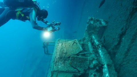 MEDITERRANEAN SEA, CYPRUS - AUGUST, 2021: Scuba diver photographer shots cabin truck on the shipwreck Swedish ferry MS Zenobia. Slow motion, Wreck diving. Mediterranean sea, Cyprus