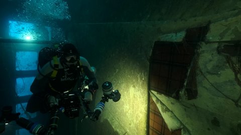 MEDITERRANEAN SEA, CYPRUS - AUGUST, 2021: Scuba diver photographer shots red carpet inside of the shipwreck Swedish ferry MS Zenobia. Wreck diving. Mediterranean sea, Cyprus
