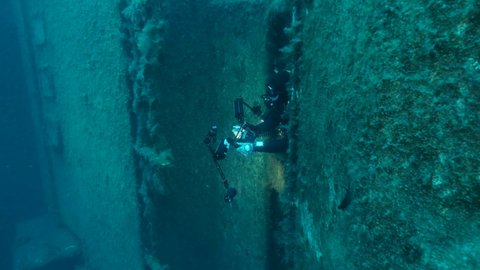 MEDITERRANEAN SEA, CYPRUS - AUGUST, 2021: Scuba diver swims out of the interior of the shipwreck Swedish ferry MS Zenobia. Wreck diving. Mediterranean sea, Cypru