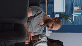 Vertical video: Interracial people using smartphones while sitting together at home. Multi ethnic couple holding devices and chatting on couch in living room. Modern mixed race lovers with technology