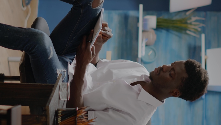 Vertical video: Person of african american ethnicity working on vase sketch for professional drawing at art studio. Black young man using craft instruments and tools for creative masterpiece and hobby