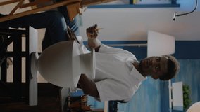 Vertical video: Artist of african american ethnicity analyzing vase for creative drawing sitting in workshop studio. Black adult with artistic imagination using inspiration for successful masterpiece