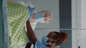 Vertical video: Caucasian family in childbirth labor getting medical assistance in hospital ward bed. Obstetrics doctor and african american nurse helping pregnant woman pushing for child delivery