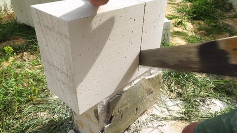 The builder cuts or cuts the block with a saw to make it into the size for the wall. A man cuts a building block with a hacksaw, so that there is accuracy in the construction site.